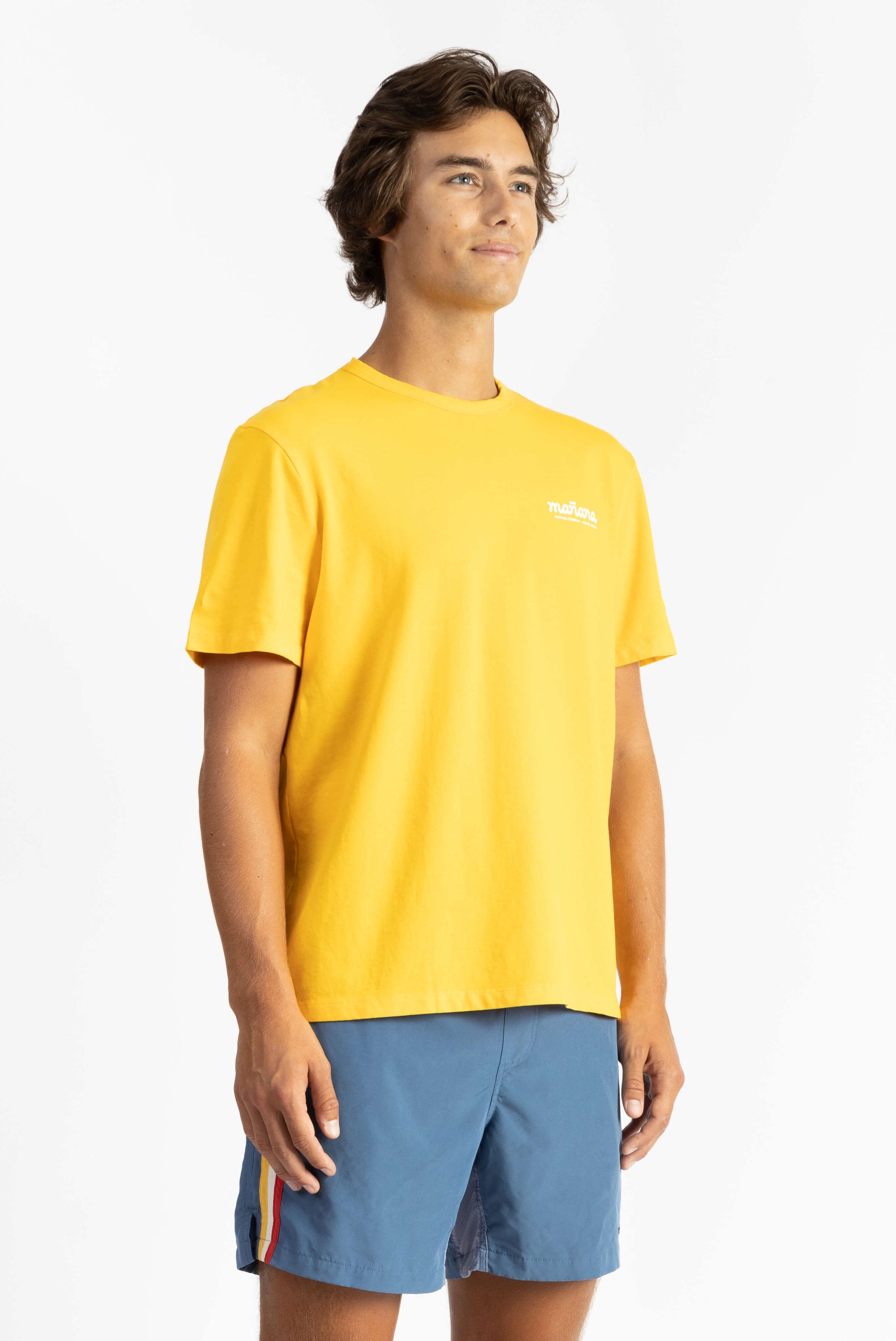 picture of a man wearing a Sun Yellow tee shirt with manana branding and blue shorts