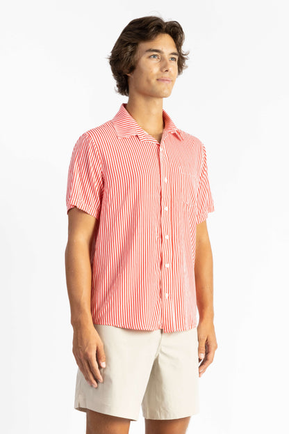 A man wearing a Red Stripes Breeze Button Up Shirt with white shorts