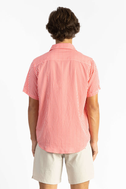 A man wearing a Red Stripes Breeze Button Up Shirt with white shorts