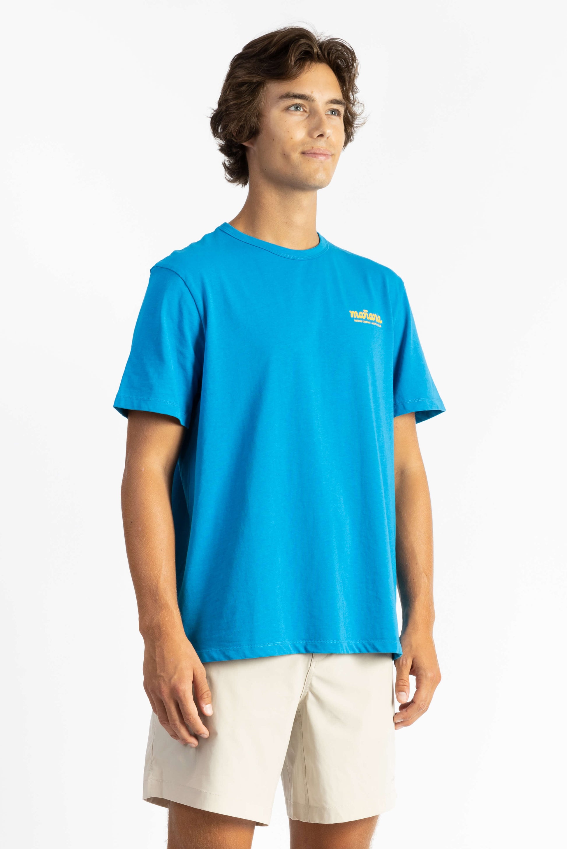 picture of a man wearing an ocean blue tee shirt with manana branding and white shorts