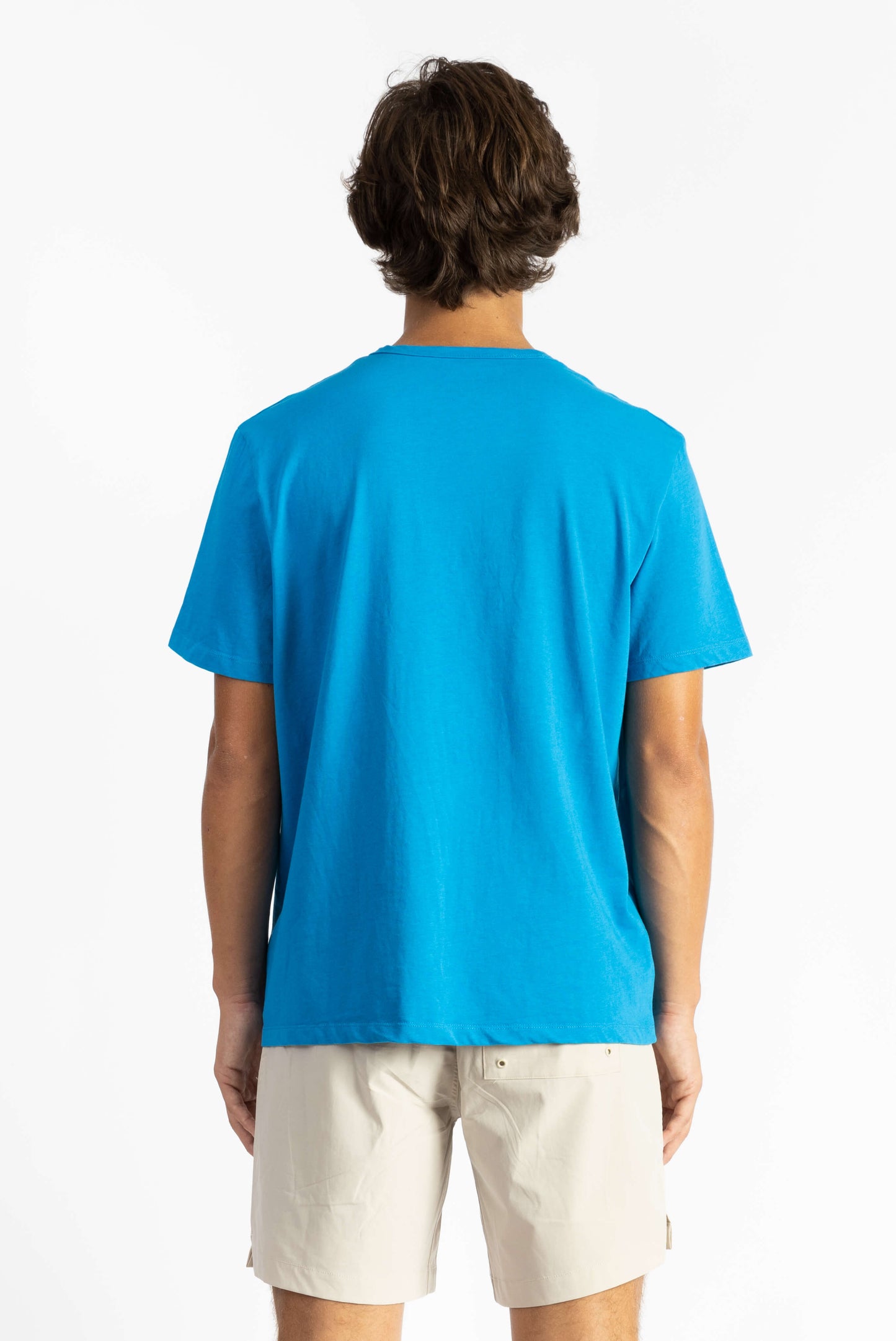 picture of a man wearing an ocean blue tee shirt with manana branding and white shorts