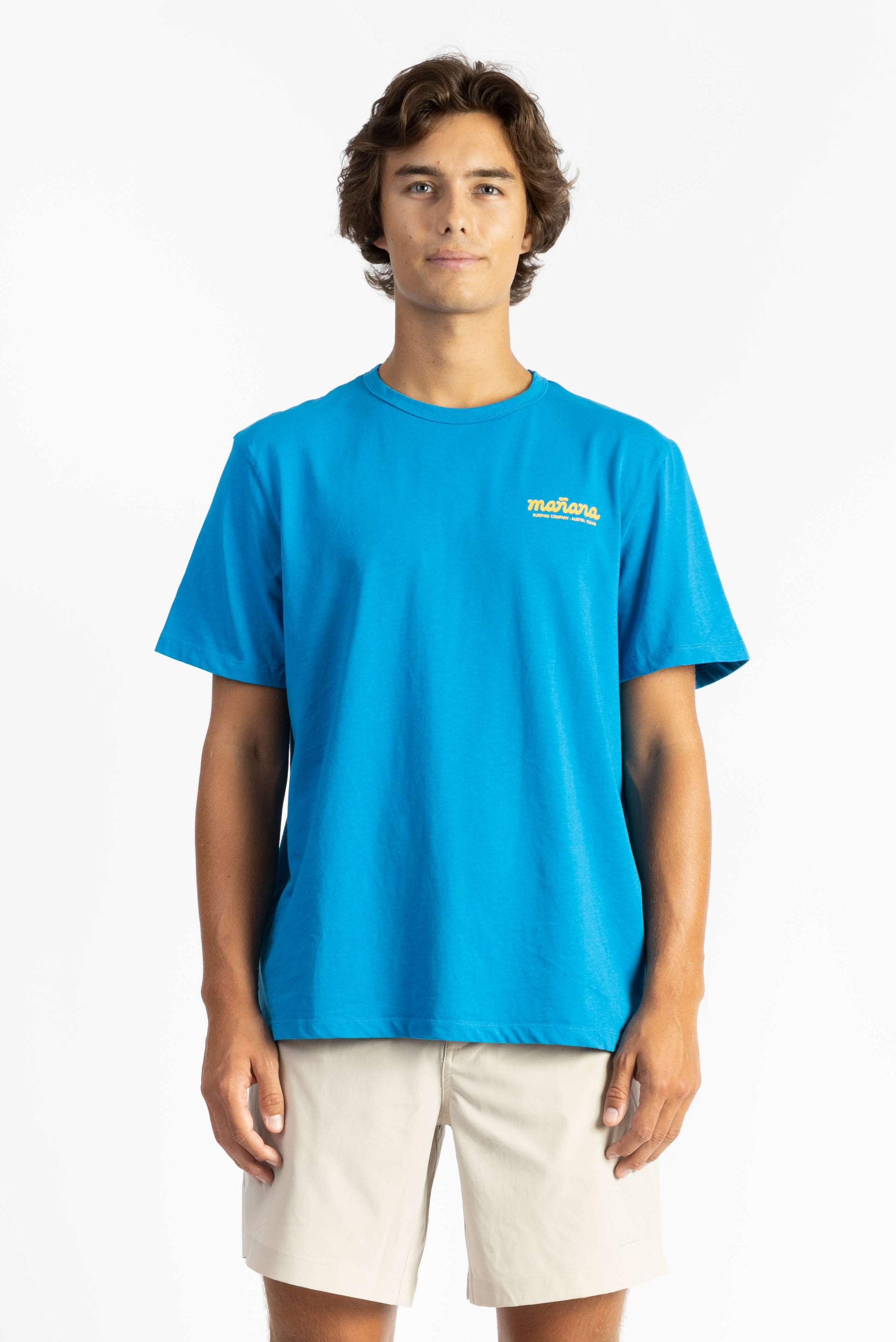 picture of a man wearing an ocean blue tee shirt with manana branding and white shorts