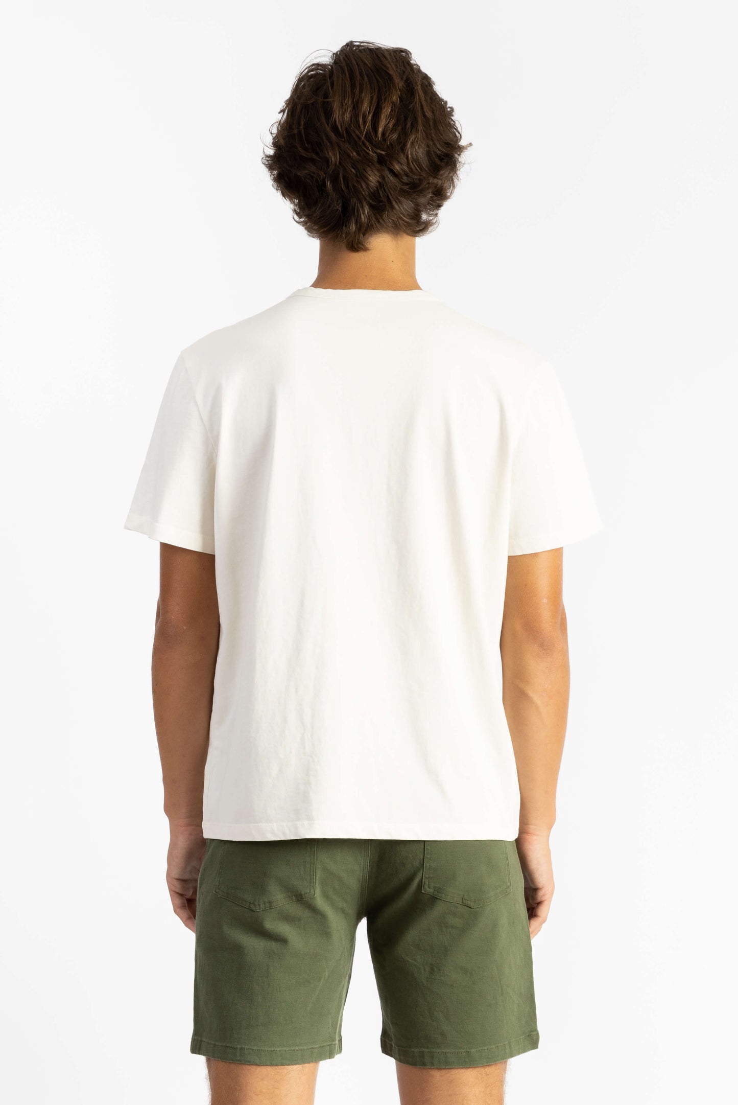 A man wearing a Off White Workshop Tee Shirt having Manana branding with green shorts