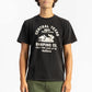 A man wearing a Black Workshop Tee Shirt having Manana branding with green shorts