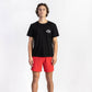 A man wearing a Washed Black Shop Tee Shirt having Manana branding with red shorts