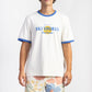 A man wearing a Ski Shores Blue Ringer Shirt having Manana branding with floral shorts