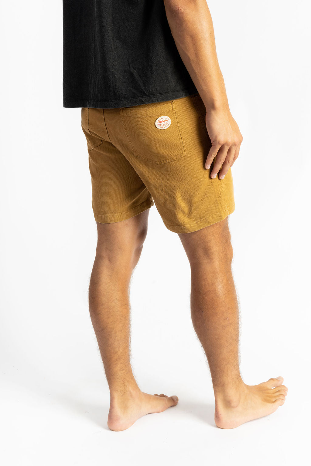 A man wearing a Sand color work short having Manana branding