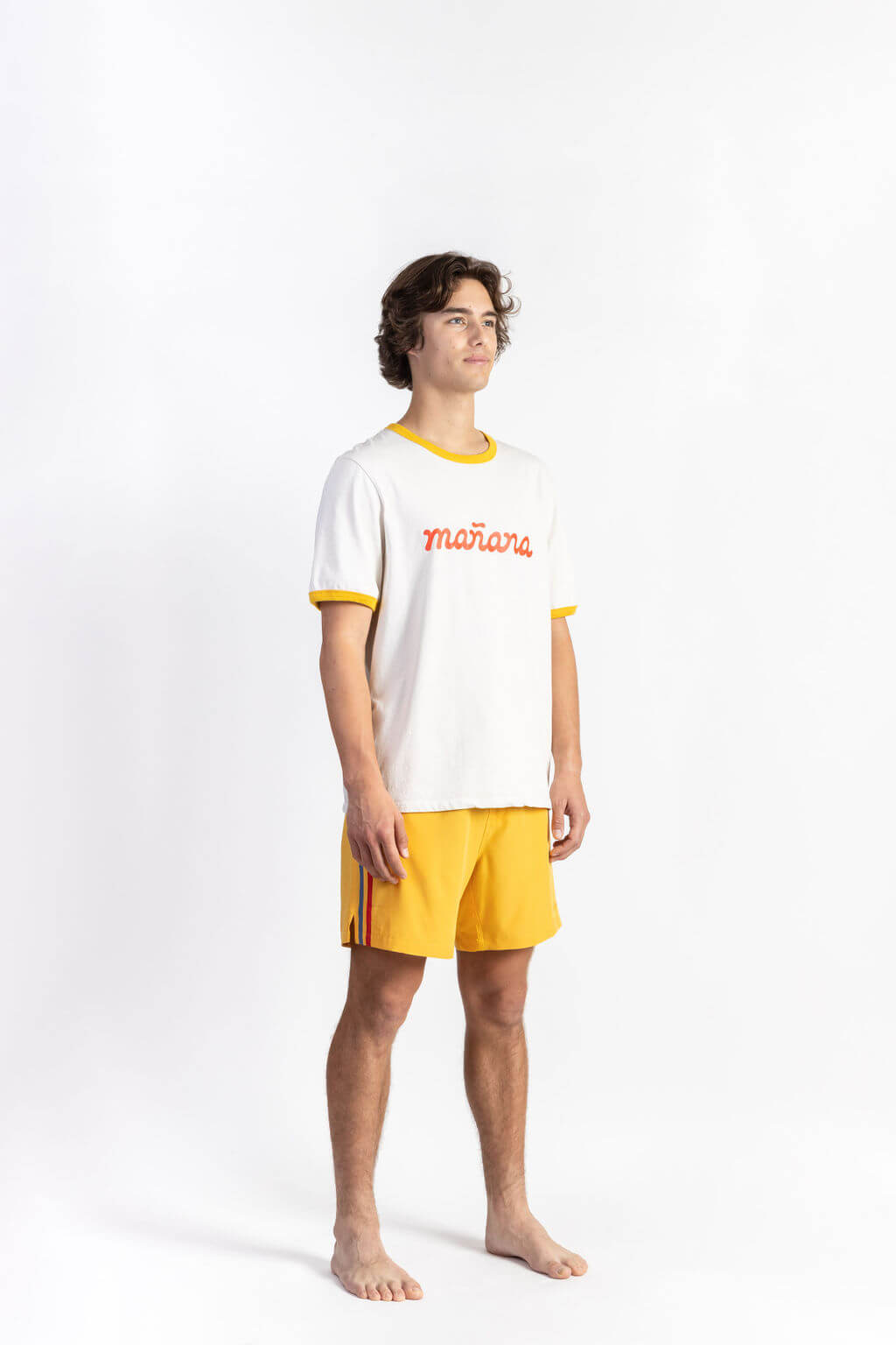 A man wearing an Off-White tee shirt having Manana branding with yellow shorts