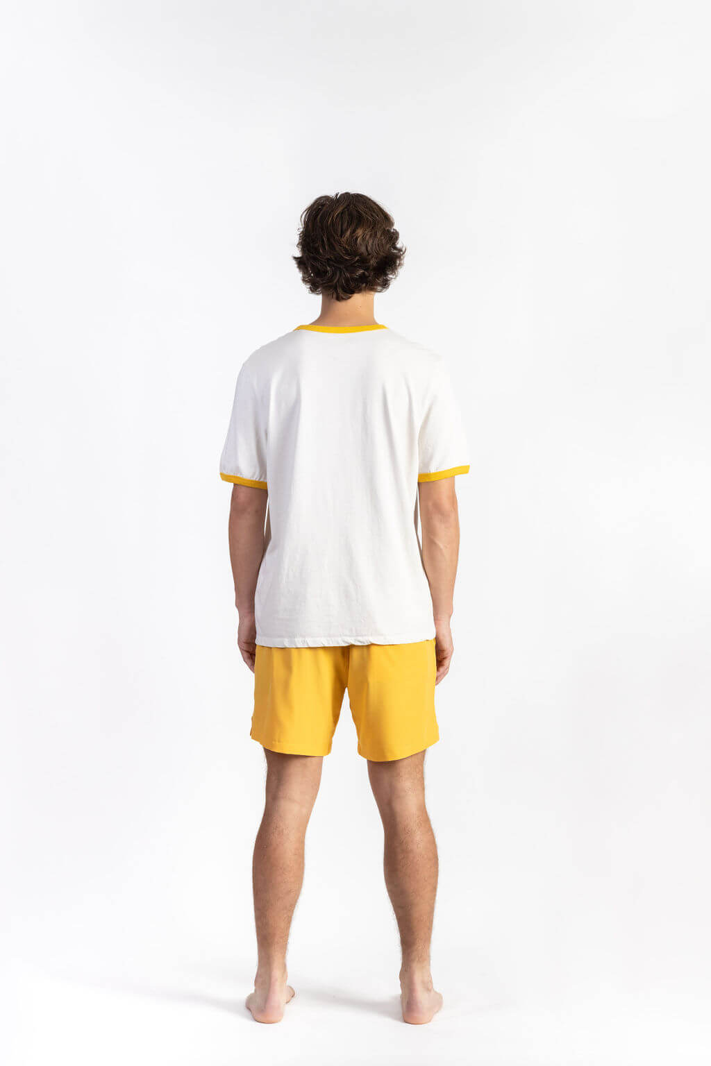 A man wearing an Off-White tee shirt having Manana branding with yellow shorts
