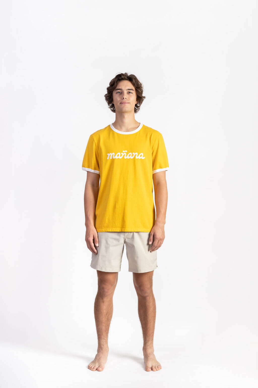 A man wearing a Yellow Logo Ringer Shirt having Manana branding with white shorts