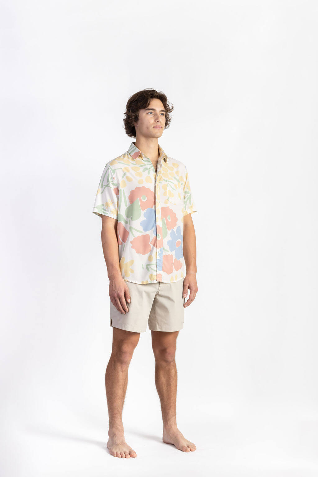 A man wearing a floral Breeze Button Up tee shirt with off white shorts