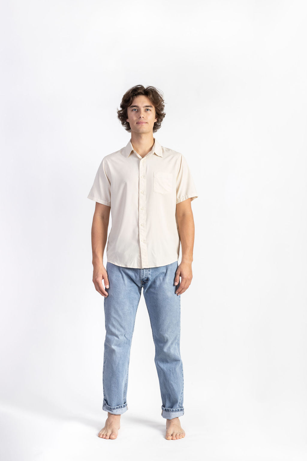A man wearing an Off-White Breeze Button Up shirt having Manana branding with blue jeans