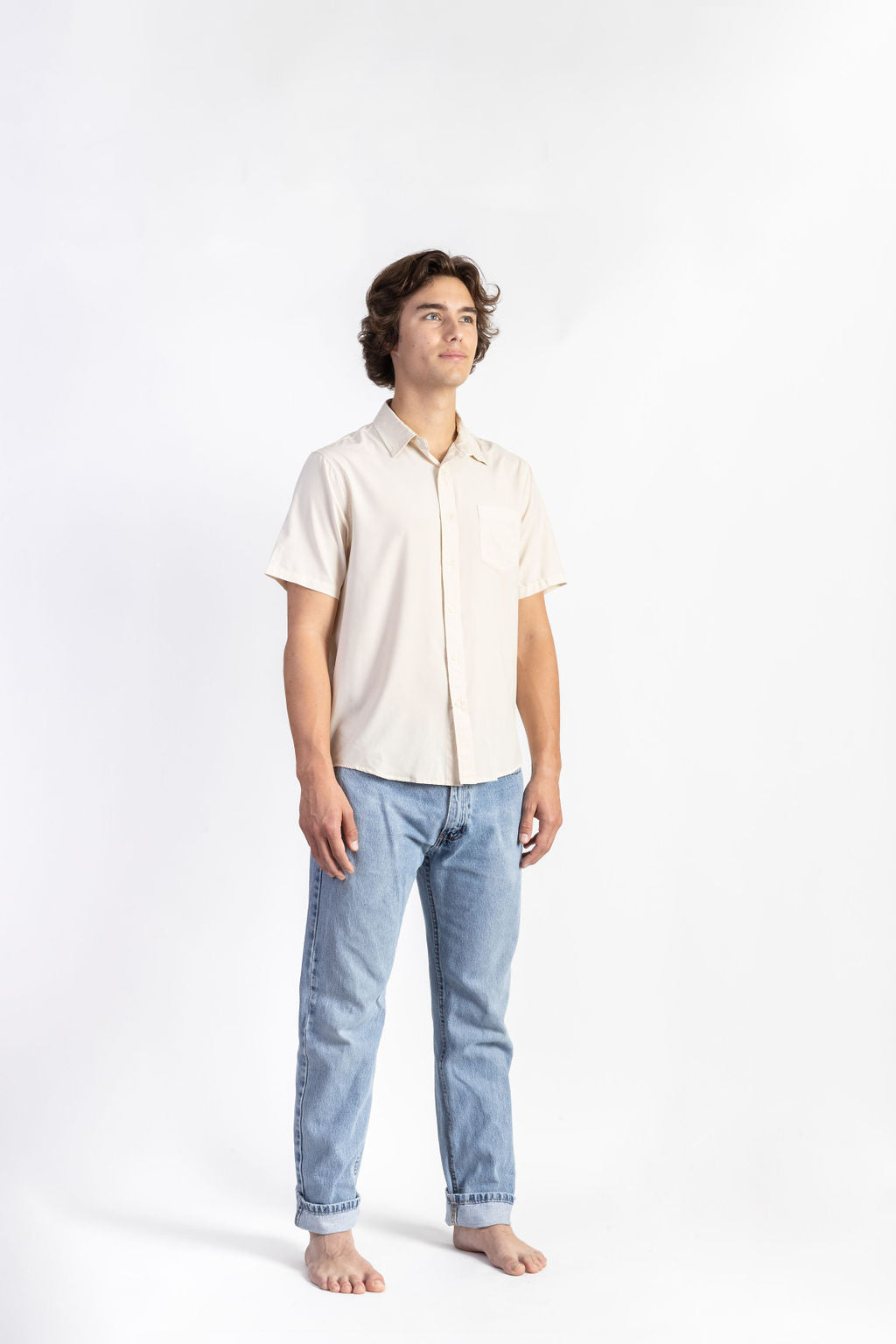 A man wearing an Off-White Breeze Button Up shirt having Manana branding with blue jeans