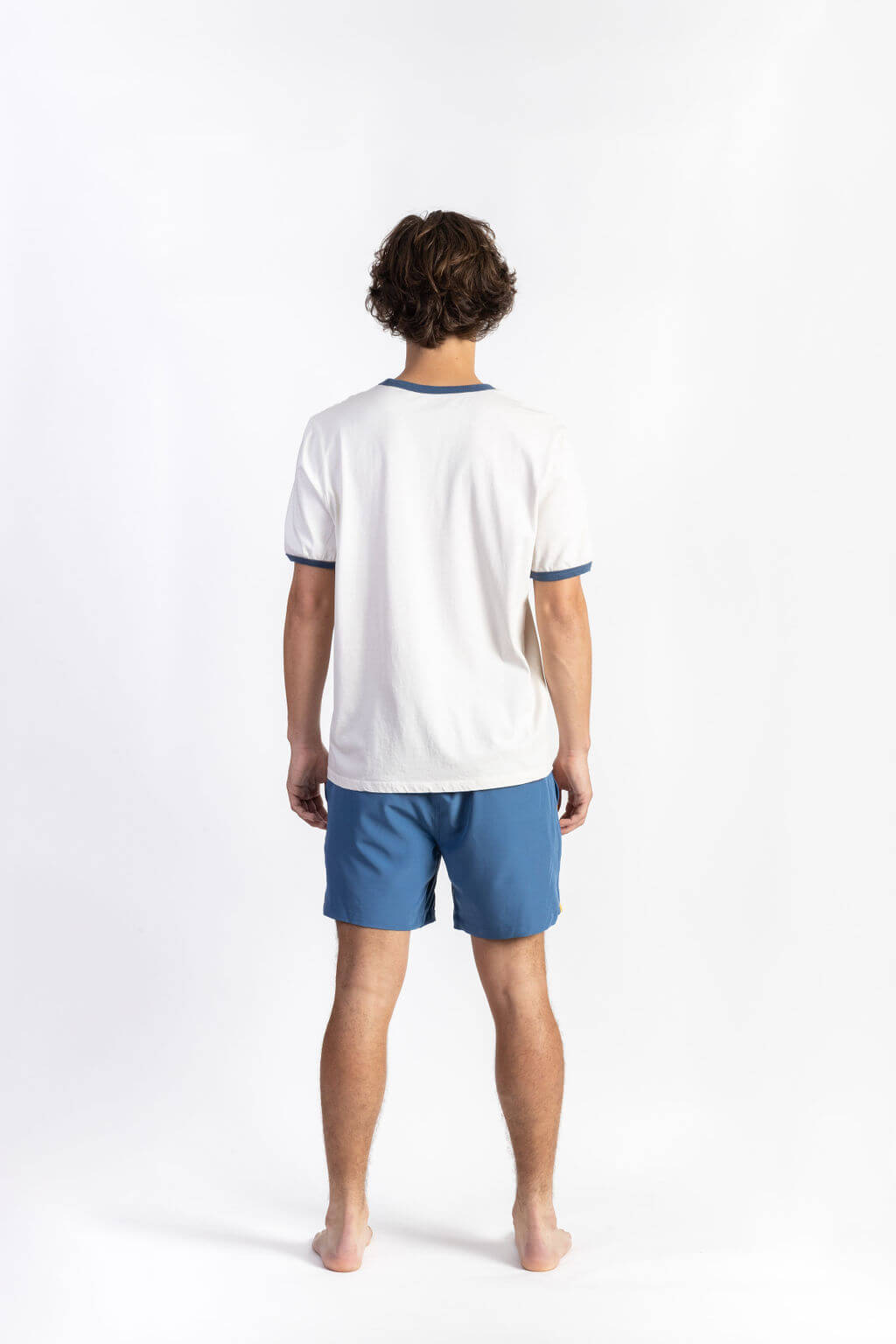 A man wearing an Off-white tee shirt having Manana branding with blue shorts