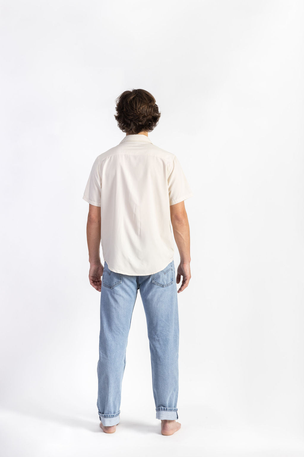 A man wearing an Off-White Breeze Button Up shirt having Manana branding with blue jeans