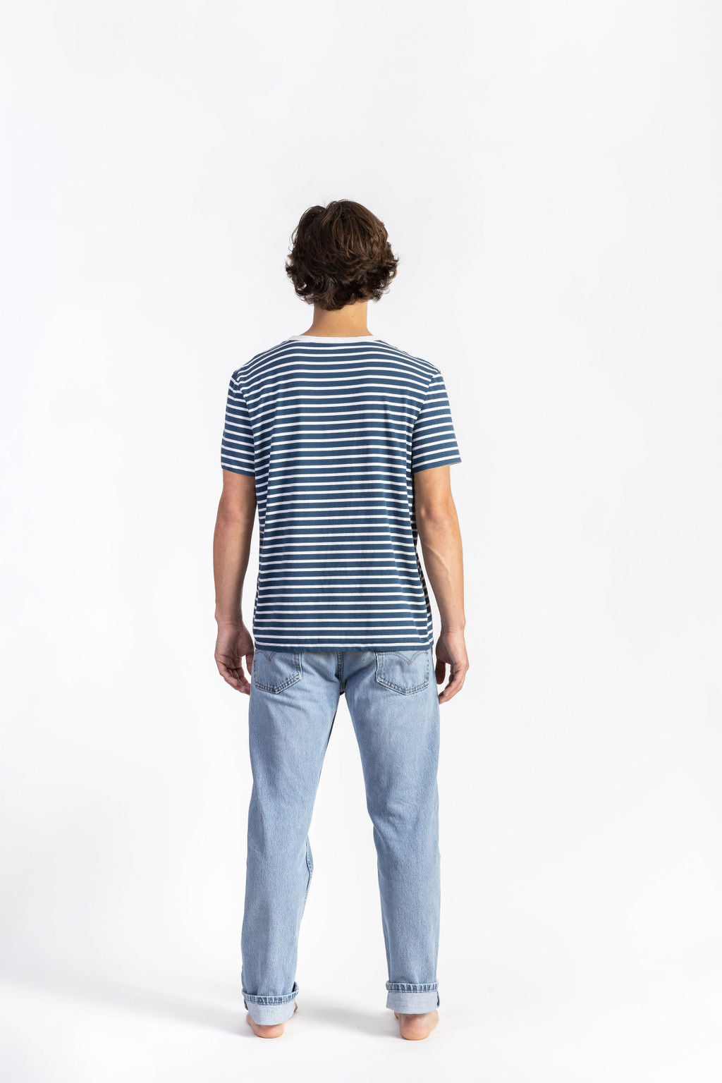 A man wearing a Blue/White Striped Tee Shirt with light blue jeans